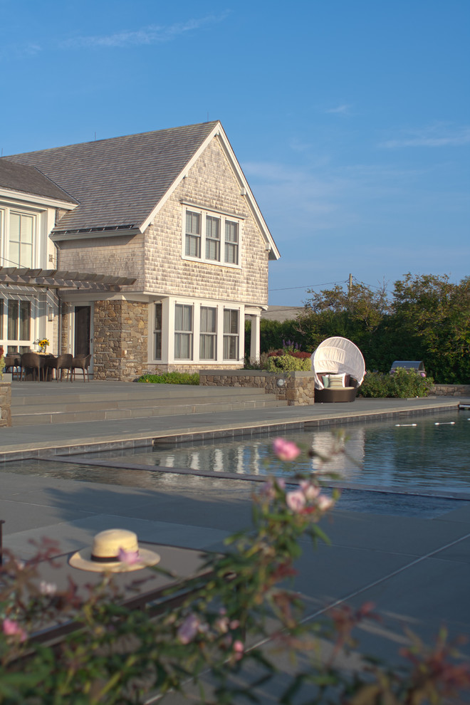 Design ideas for a beach style rectangular lap pool in Providence with natural stone pavers.