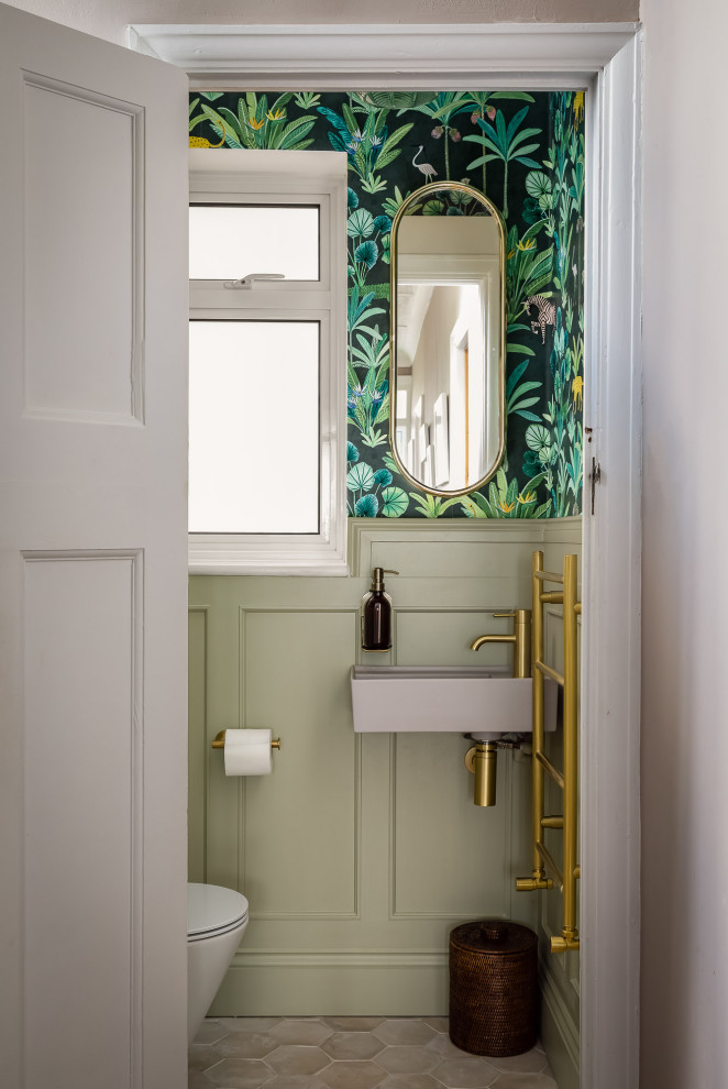 Inspiration for a small eclectic powder room in London with grey cabinets, a wall-mount toilet, porcelain floors, a wall-mount sink, white floor and a floating vanity.