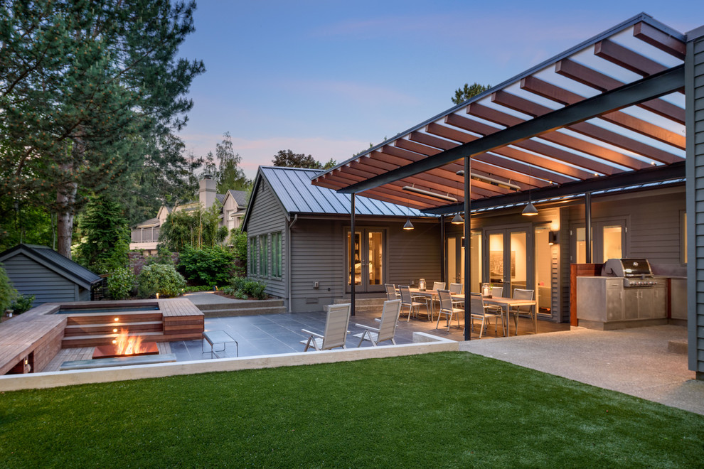 This is an example of a large contemporary backyard patio in Other with an outdoor kitchen, tile and an awning.