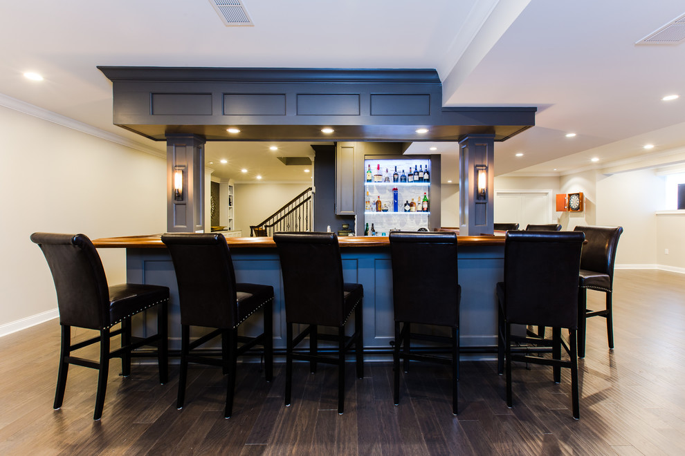 Photo of a large contemporary u-shaped seated home bar in Philadelphia with an undermount sink, recessed-panel cabinets, black cabinets, wood benchtops, white splashback, stone tile splashback, dark hardwood floors, brown floor and brown benchtop.