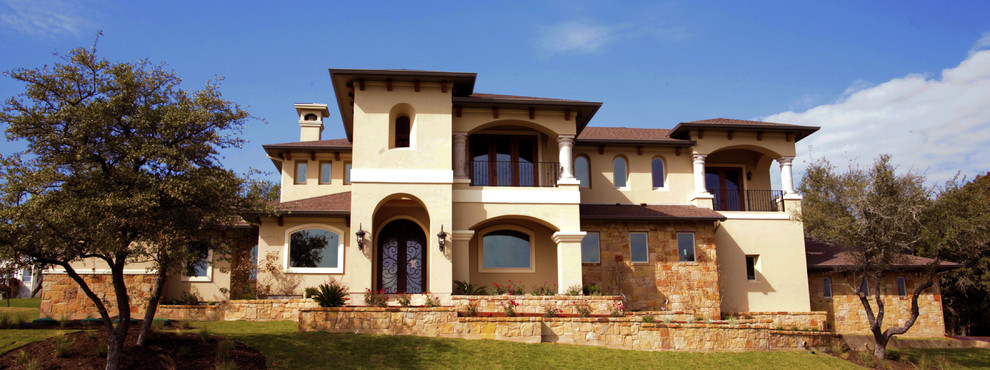 This is an example of a large mediterranean two-storey stucco beige exterior in Austin with a hip roof.