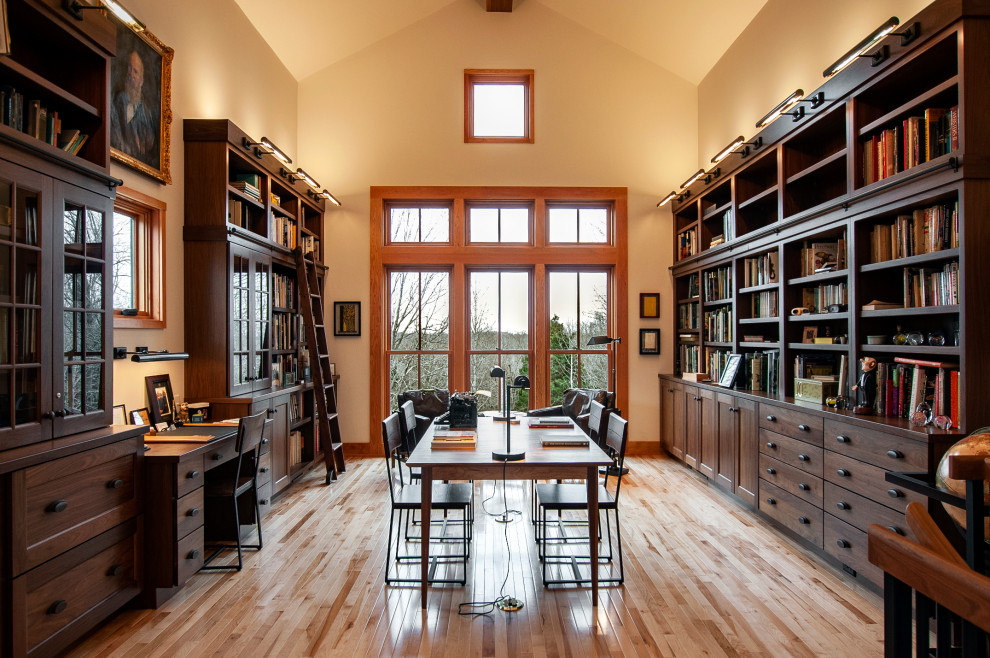 Home office library - large craftsman built-in desk light wood floor, brown floor and vaulted ceiling home office library idea in Nashville with white walls