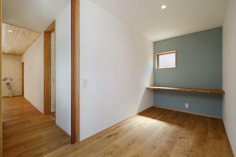 Kleines Asiatisches Nähzimmer ohne Kamin mit weißer Wandfarbe, braunem Holzboden, Einbau-Schreibtisch, braunem Boden, Tapetendecke und Tapetenwänden in Sonstige