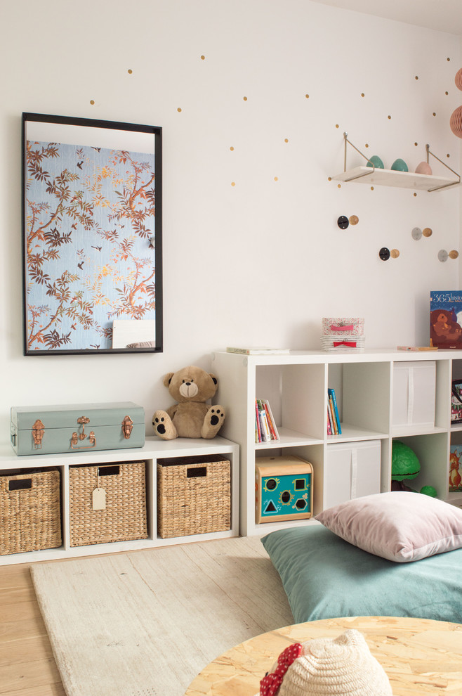 Design ideas for a transitional gender-neutral kids' playroom in Lyon with white walls and light hardwood floors.