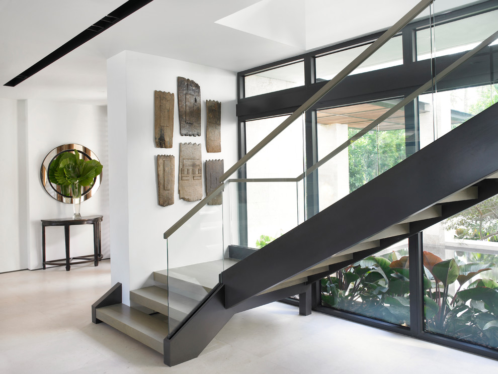 Beach style concrete l-shaped staircase in Miami with open risers and glass railing.