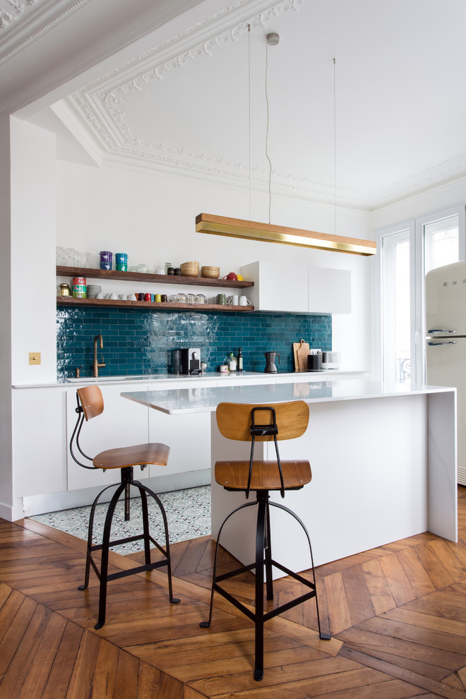 Inspiration for a mid-sized contemporary galley open plan kitchen in Paris with marble benchtops, blue splashback, ceramic splashback, cement tiles, with island, white benchtop, flat-panel cabinets, white cabinets, white appliances and multi-coloured floor.