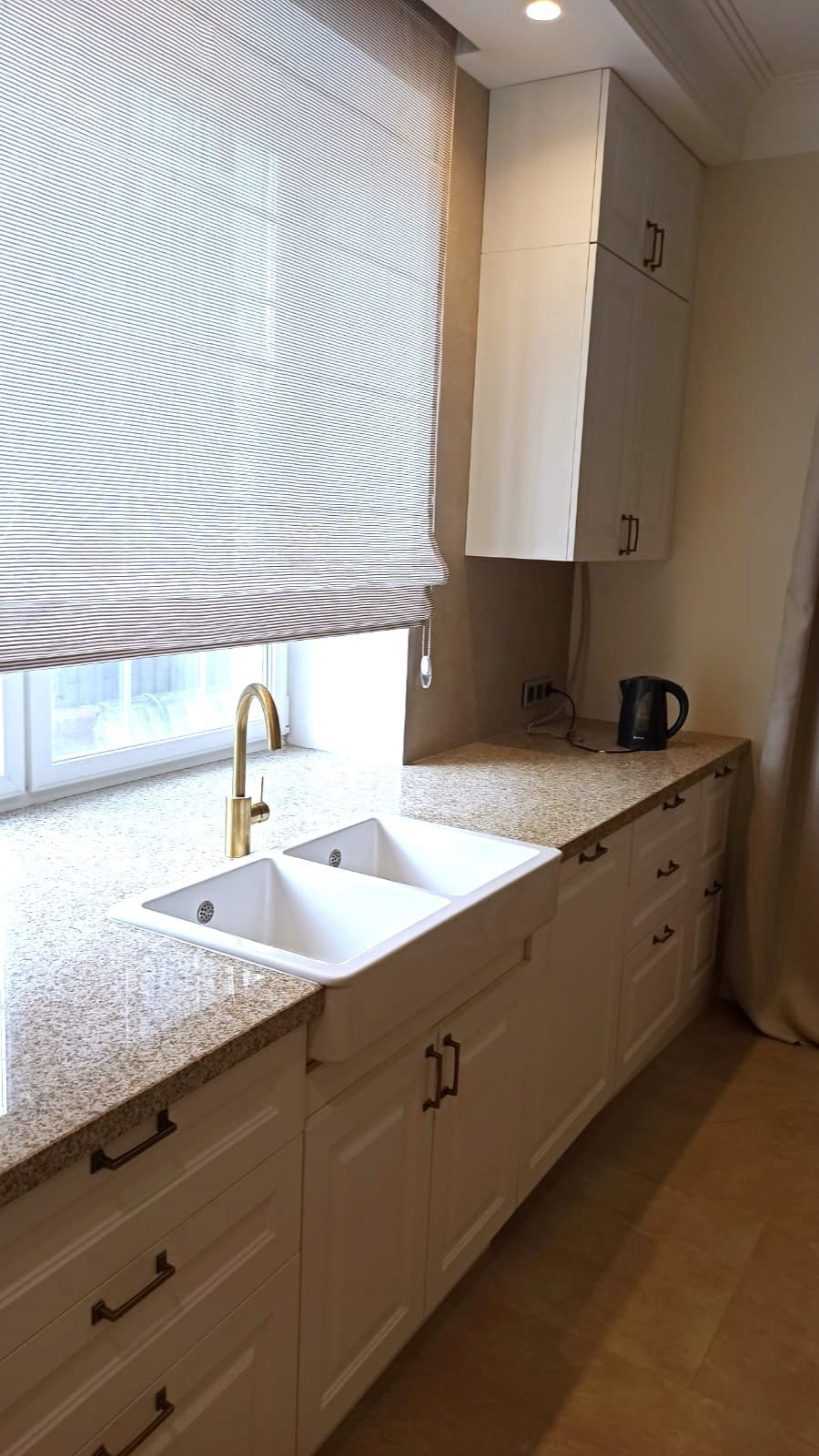 Угловая кухня в белом цвете с раковиной у окна