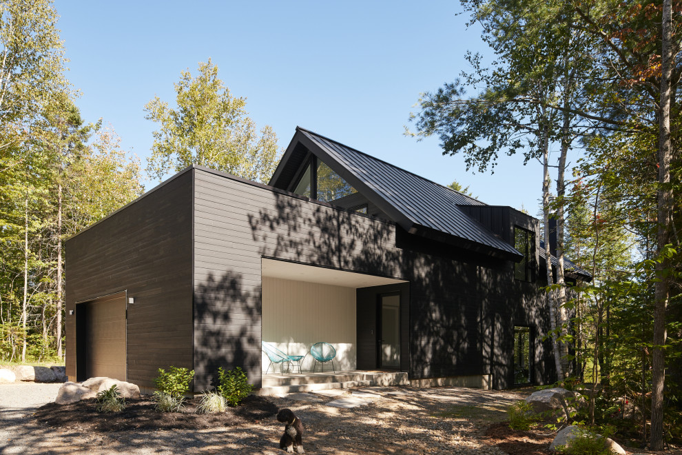 Inspiration pour une façade de maison noire design en bois et bardage à clin de taille moyenne et à un étage avec un toit à deux pans, un toit en métal et un toit noir.