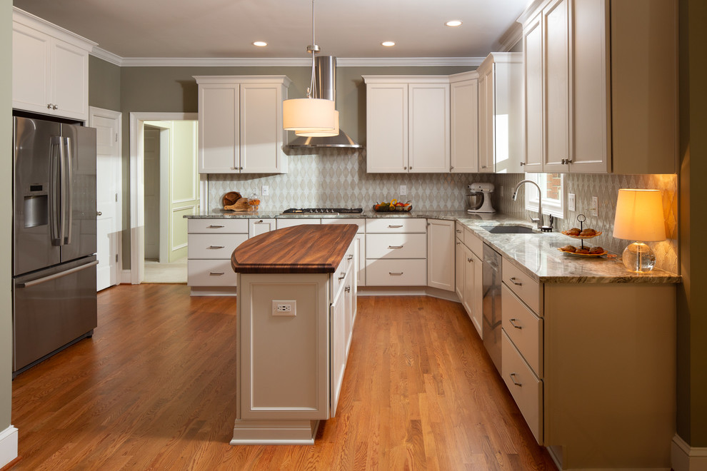 This is an example of a mid-sized transitional u-shaped kitchen in Atlanta with an undermount sink, recessed-panel cabinets, white cabinets, quartzite benchtops, mosaic tile splashback, stainless steel appliances, medium hardwood floors, with island, brown floor, grey splashback and grey benchtop.