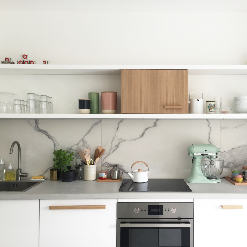 Inspiration for a mid-sized contemporary single-wall open plan kitchen in Marseille with an undermount sink, beaded inset cabinets, white cabinets, concrete benchtops, white splashback, marble splashback, panelled appliances, concrete floors, with island, grey floor and grey benchtop.
