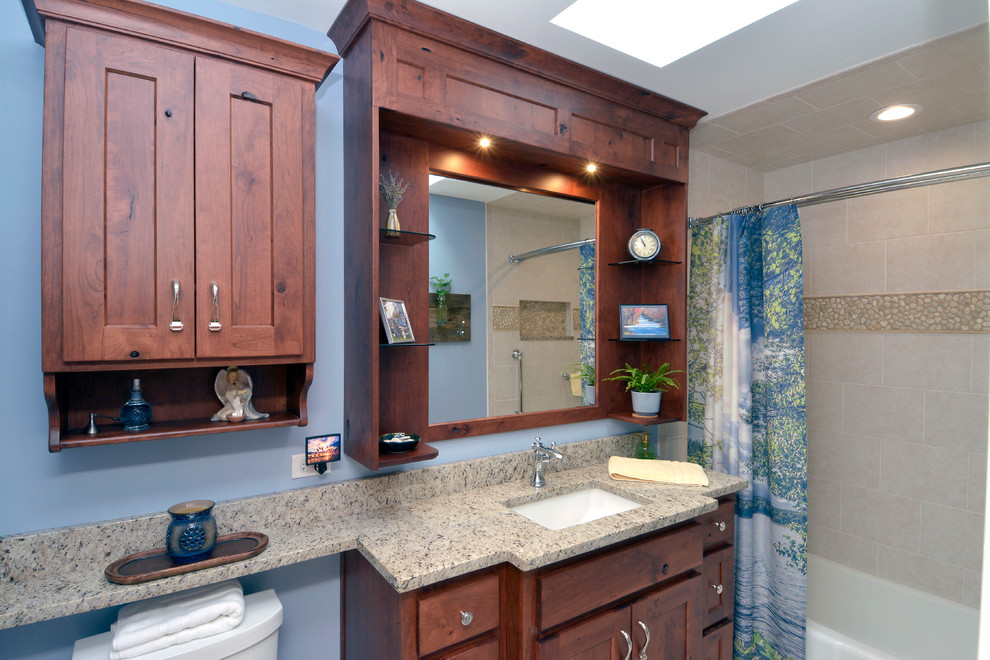 Mid-sized transitional master bathroom in Chicago with recessed-panel cabinets, medium wood cabinets, an alcove tub, an alcove shower, a two-piece toilet, beige tile, ceramic tile, blue walls, ceramic floors, an undermount sink and granite benchtops.