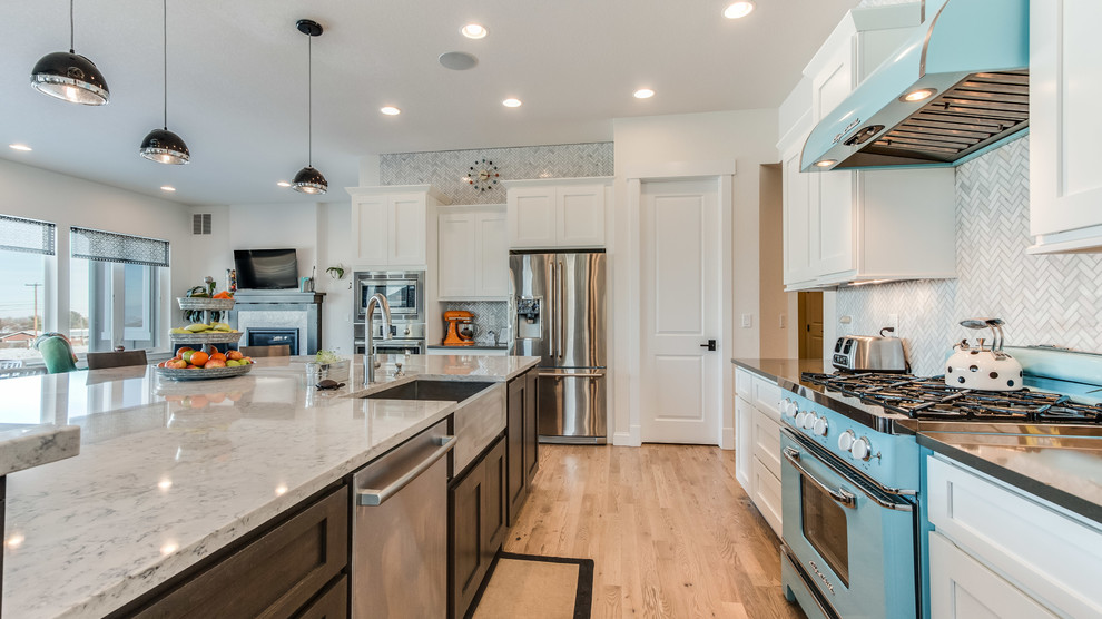 Example of a large transitional l-shaped light wood floor open concept kitchen design in Denver with a farmhouse sink, shaker cabinets, white cabinets, marble countertops, gray backsplash, matchstick tile backsplash, stainless steel appliances and an island