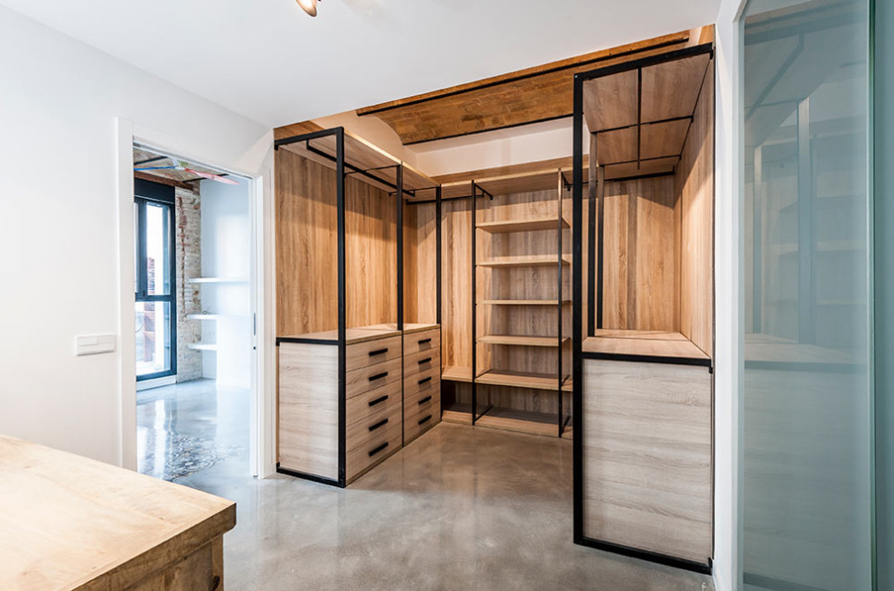 Photo of a large midcentury walk-in wardrobe in Valencia with light wood cabinets, concrete floors, grey floor and exposed beam.