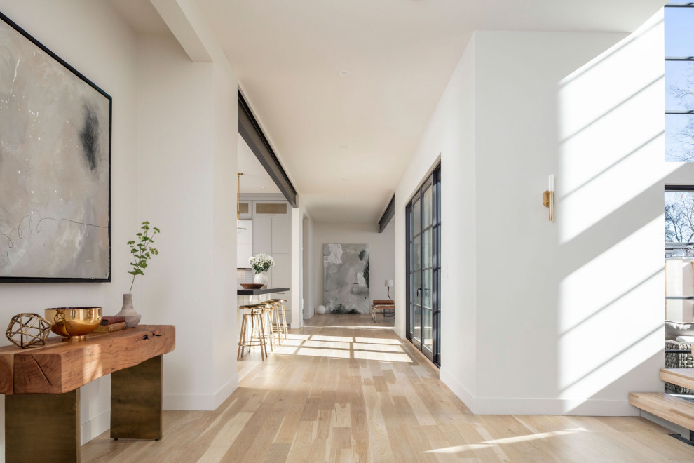Example of a large minimalist light wood floor and beige floor entry hall design in Denver with white walls