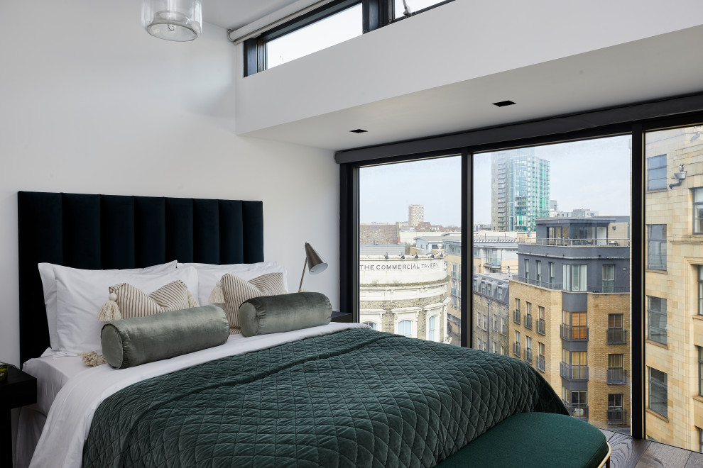 Photo of a medium sized industrial master bedroom in London with white walls, dark hardwood flooring and brown floors.