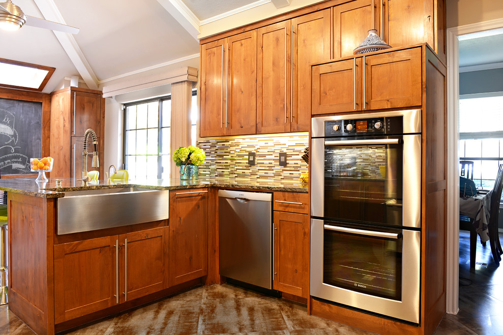 Eat-in kitchen - large transitional u-shaped travertine floor eat-in kitchen idea in Dallas with a farmhouse sink, medium tone wood cabinets, granite countertops, multicolored backsplash, matchstick tile backsplash, stainless steel appliances and a peninsula