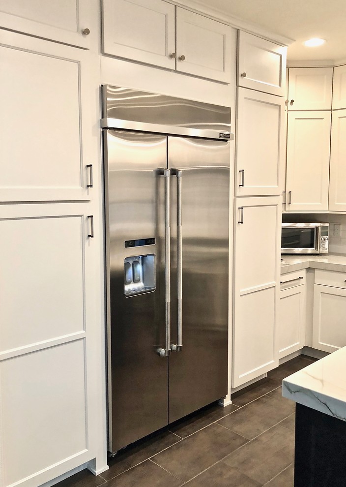 This is an example of a mid-sized country l-shaped separate kitchen in Las Vegas with a farmhouse sink, shaker cabinets, white cabinets, marble benchtops, white splashback, subway tile splashback, stainless steel appliances, concrete floors, with island, grey floor and white benchtop.