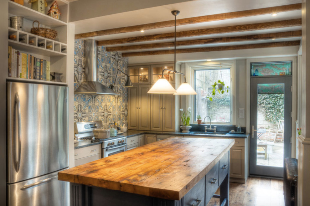 Inspiration for a mid-sized rustic l-shaped light wood floor and brown floor enclosed kitchen remodel in Vancouver with an undermount sink, raised-panel cabinets, gray cabinets, soapstone countertops, multicolored backsplash, ceramic backsplash, stainless steel appliances and an island
