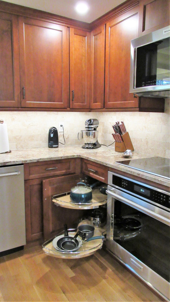 Example of a mid-sized transitional u-shaped light wood floor and brown floor enclosed kitchen design in Boston with an undermount sink, recessed-panel cabinets, brown cabinets, granite countertops, beige backsplash, stainless steel appliances, no island and beige countertops