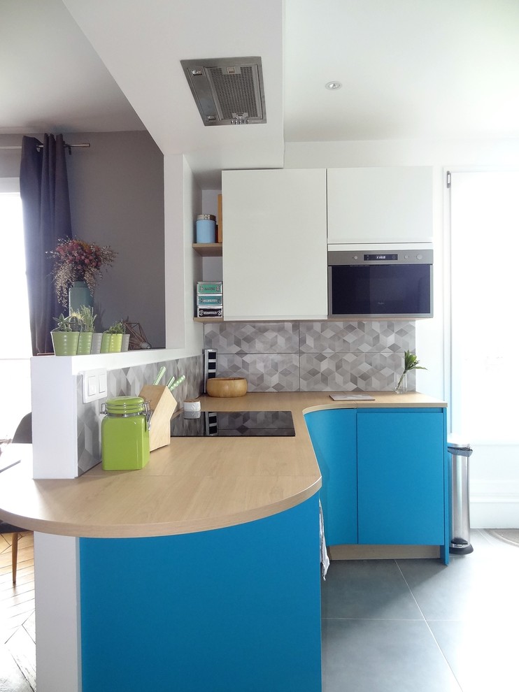 Photo of a small scandinavian l-shaped eat-in kitchen in Paris with beaded inset cabinets, blue cabinets, wood benchtops, grey splashback, ceramic splashback, panelled appliances, ceramic floors, no island and grey floor.