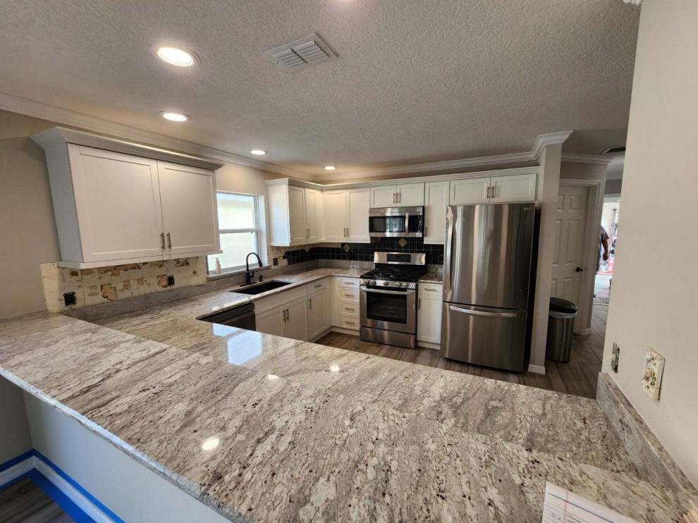Large galley kitchen photo with shaker cabinets, white cabinets, quartz countertops, an island and white countertops