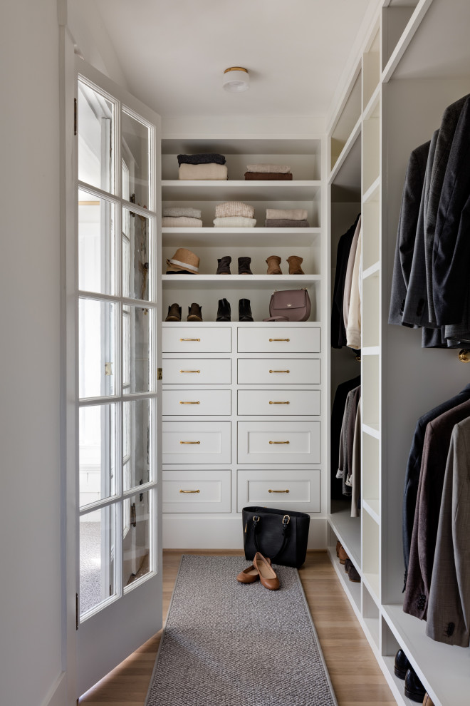 Inspiration for a mid-sized transitional gender-neutral walk-in wardrobe in Seattle with beaded inset cabinets, white cabinets, light hardwood floors and brown floor.
