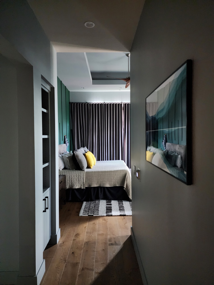 Photo of a large modern master bedroom in Austin with green walls, light hardwood flooring and a drop ceiling.