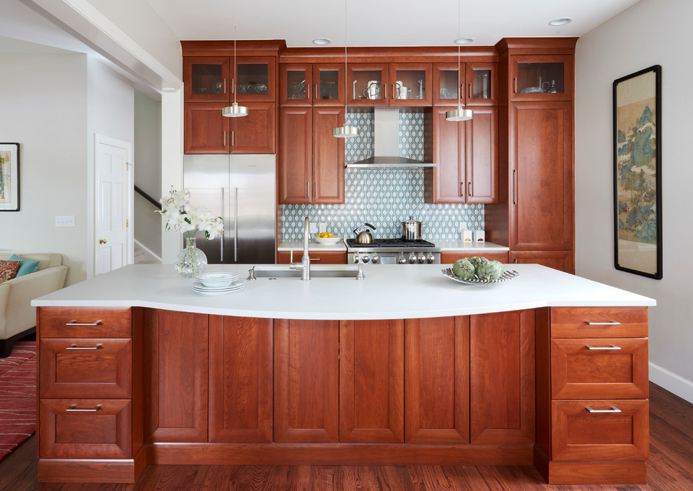 Inspiration for a mid-sized transitional galley medium tone wood floor eat-in kitchen remodel in Denver with a single-bowl sink, recessed-panel cabinets, medium tone wood cabinets, solid surface countertops, green backsplash, glass tile backsplash, stainless steel appliances and an island