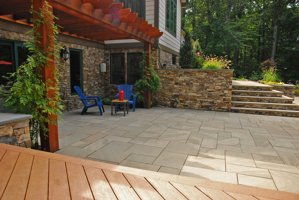 This is an example of a large asian backyard patio in DC Metro with an outdoor kitchen, natural stone pavers and a pergola.