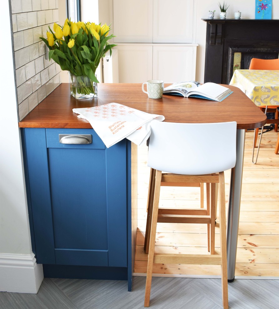 Inspiration for a medium sized contemporary u-shaped kitchen/diner with a belfast sink, shaker cabinets, blue cabinets, recycled glass countertops, white splashback, ceramic splashback, lino flooring, a breakfast bar and grey floors.