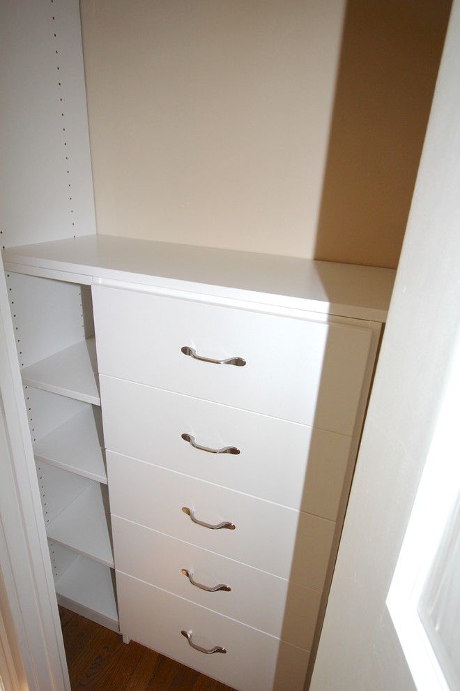 This is an example of a small traditional gender-neutral built-in wardrobe in Other with flat-panel cabinets, white cabinets and dark hardwood floors.