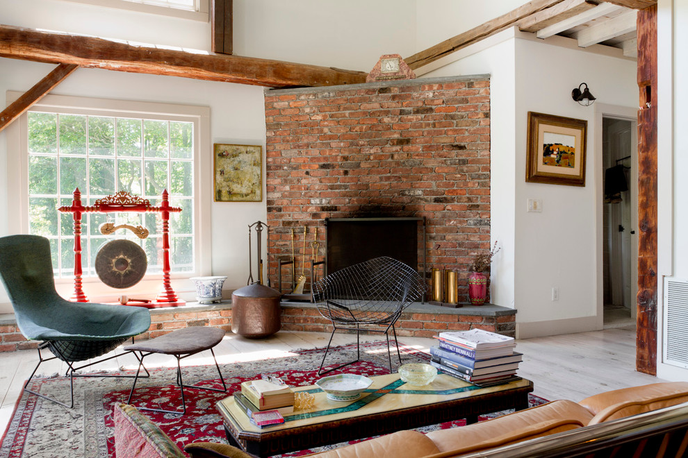 This is an example of an eclectic open concept living room in New York with white walls, a corner fireplace and a brick fireplace surround.
