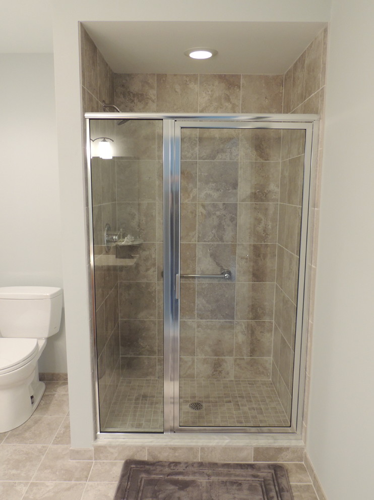 This is an example of a mid-sized traditional 3/4 bathroom in Detroit with shaker cabinets, medium wood cabinets, an alcove shower, a one-piece toilet, beige tile, stone tile, grey walls, limestone floors, a drop-in sink and laminate benchtops.