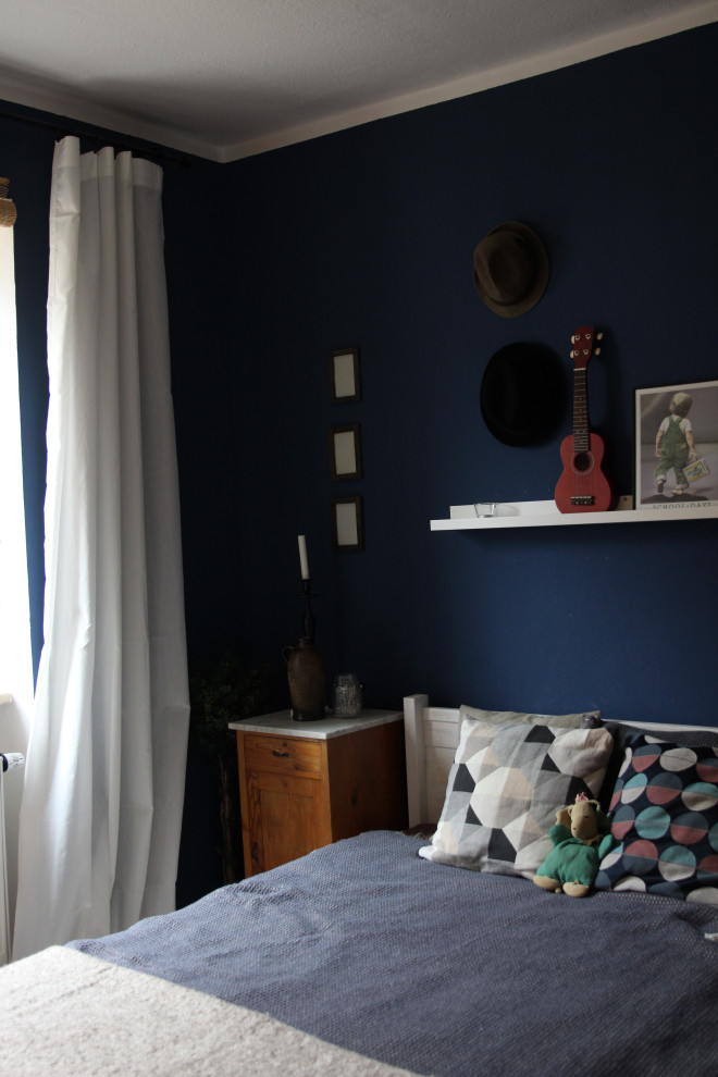 Cette photo montre une petite chambre parentale éclectique avec un mur bleu, sol en stratifié et un sol marron.