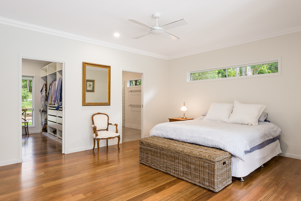 This is an example of a country master bedroom in Brisbane with grey walls, medium hardwood floors and brown floor.
