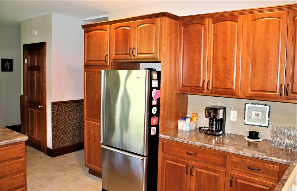 Mid-sized mountain style l-shaped vinyl floor and beige floor eat-in kitchen photo with a farmhouse sink, raised-panel cabinets, medium tone wood cabinets, laminate countertops, beige backsplash, cement tile backsplash, stainless steel appliances, a peninsula and beige countertops