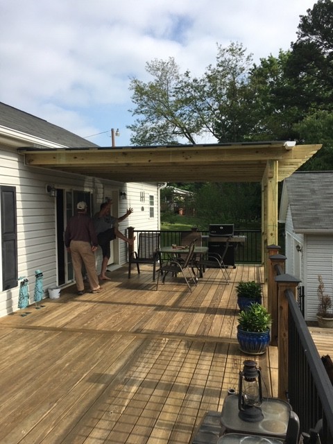 Design ideas for a mid-sized country backyard deck in Charlotte with a roof extension.