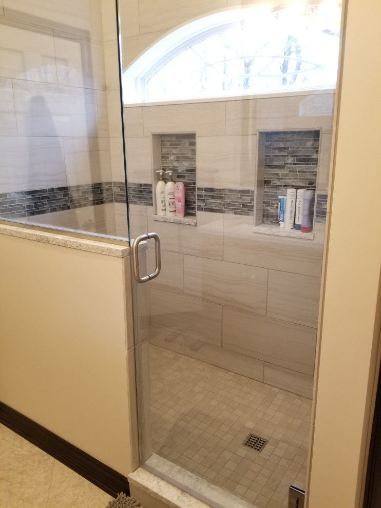 Design ideas for a large traditional master bathroom in Cleveland with raised-panel cabinets, brown cabinets, an alcove shower, a two-piece toilet, white tile, ceramic tile, beige walls, laminate floors, an undermount sink, engineered quartz benchtops, beige floor, a hinged shower door and white benchtops.