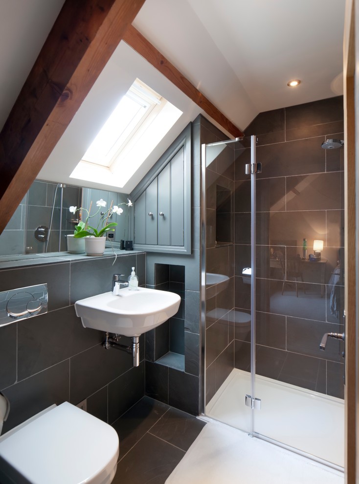 Photo of a transitional bathroom in Gloucestershire with a wall-mount sink, an alcove shower, a wall-mount toilet, gray tile, stone slab, grey walls and slate floors.