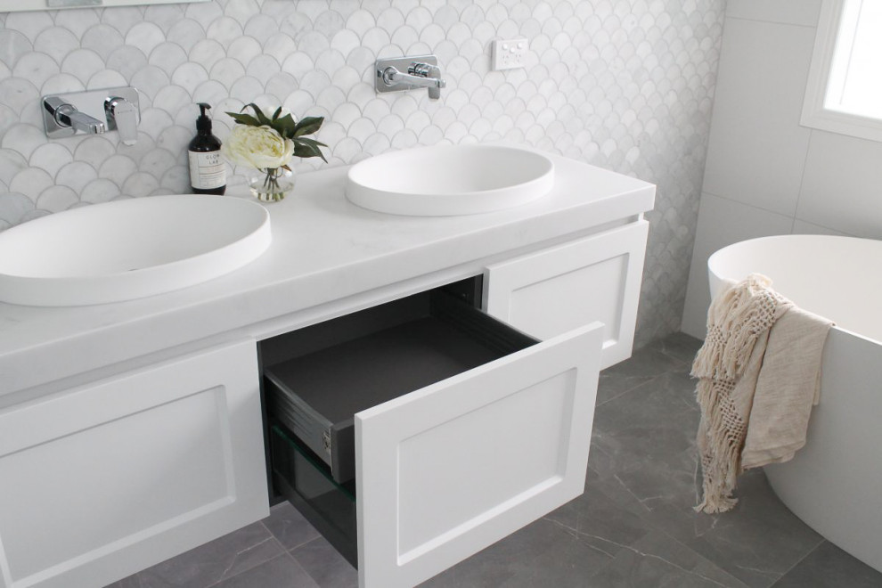 Modern inredning av ett stort grå grått badrum med dusch, med skåp i shakerstil, vita skåp, ett badkar med tassar, en öppen dusch, en toalettstol med hel cisternkåpa, flerfärgad kakel, keramikplattor, grå väggar, klinkergolv i porslin, ett nedsänkt handfat, bänkskiva i akrylsten, grått golv och med dusch som är öppen