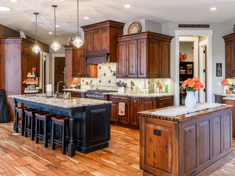 Inspiration for a rustic medium tone wood floor open concept kitchen remodel with a farmhouse sink, dark wood cabinets, granite countertops, beige backsplash, an island and white countertops
