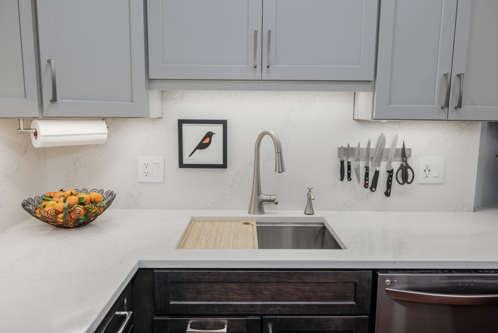 Foto på ett mellanstort vintage vit kök, med en undermonterad diskho, skåp i shakerstil, grå skåp, bänkskiva i kvarts, vitt stänkskydd, stänkskydd i sten, svarta vitvaror, mellanmörkt trägolv, en halv köksö och orange golv