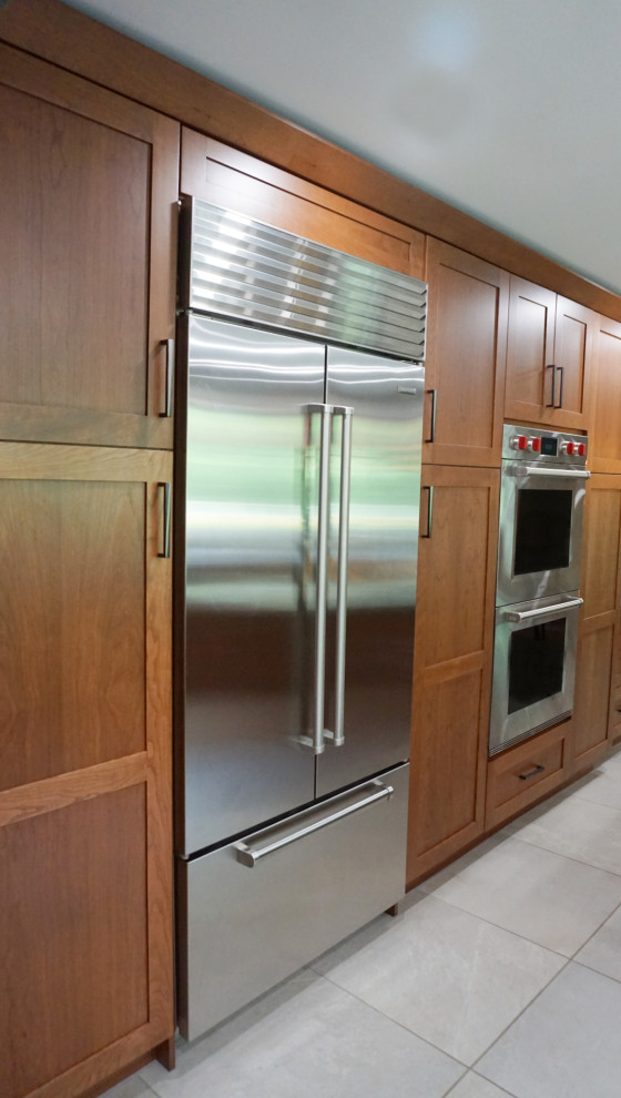 Mid-sized transitional porcelain tile and gray floor eat-in kitchen photo with recessed-panel cabinets, medium tone wood cabinets, quartzite countertops, green backsplash, mosaic tile backsplash, stainless steel appliances and an island