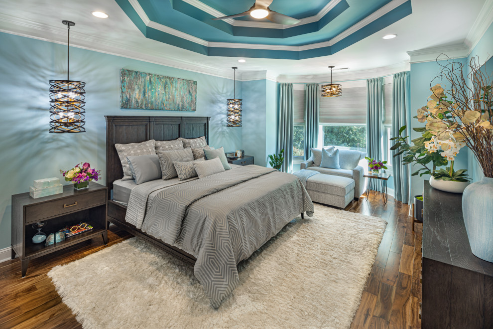 Exemple d'une grande chambre parentale tendance avec un mur bleu, un sol en bois brun, un sol marron et un plafond décaissé.