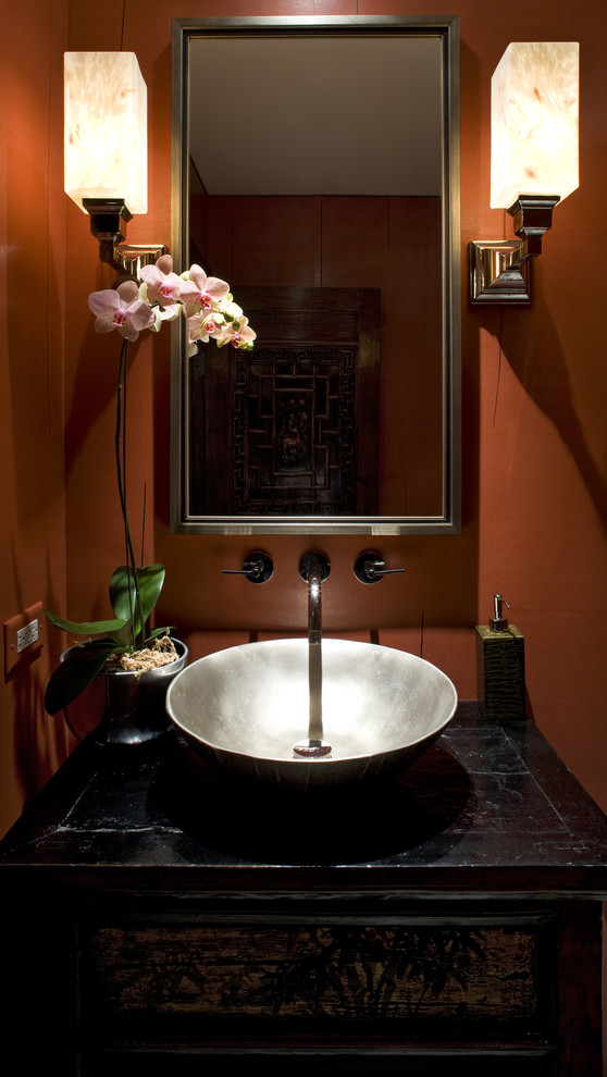 This is an example of a small asian powder room in Chicago with a vessel sink, furniture-like cabinets, black cabinets, a one-piece toilet, beige tile, red walls, marble floors, wood benchtops and black benchtops.