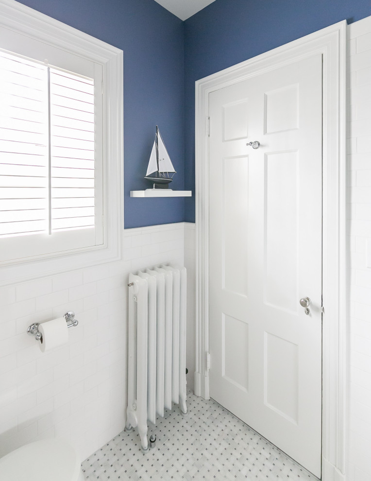 This is an example of a small traditional kids bathroom in Baltimore with white cabinets, a two-piece toilet, blue tile, ceramic tile, blue walls, marble floors, a pedestal sink, white floor, a hinged shower door, a niche, a double vanity, a freestanding vanity and decorative wall panelling.