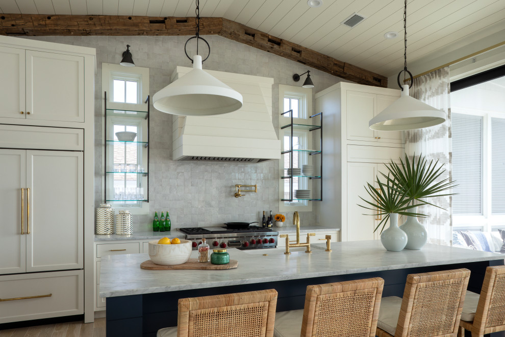 Design ideas for a large beach style single-wall open plan kitchen in Other with a farmhouse sink, recessed-panel cabinets, white cabinets, granite benchtops, grey splashback, ceramic splashback, white appliances, painted wood floors, with island, beige floor, grey benchtop and exposed beam.