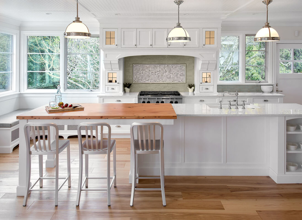 This is an example of a large traditional eat-in kitchen in Vancouver with a farmhouse sink, shaker cabinets, wood benchtops, metallic splashback, stainless steel appliances, light hardwood floors and with island.