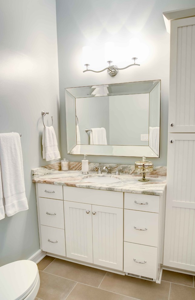 Small traditional bathroom in Raleigh with beaded inset cabinets, white cabinets, granite benchtops, a drop-in tub, a shower/bathtub combo, white tile, porcelain tile, a two-piece toilet, grey walls, porcelain floors, an undermount sink, brown floor and a shower curtain.