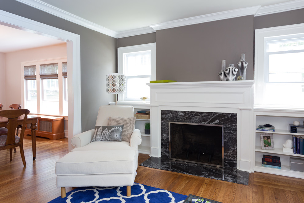 Mid-sized transitional family room in New York with grey walls, medium hardwood floors, a standard fireplace, a stone fireplace surround and no tv.